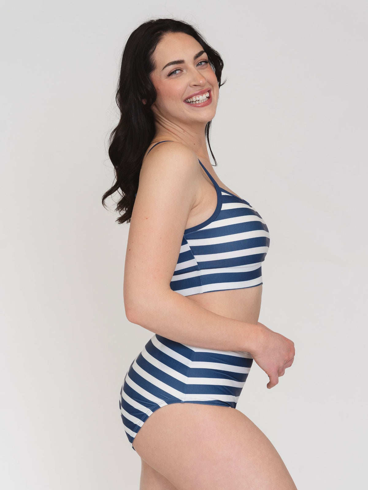 Woman wearing a blue and white striped swimsuit on a plain background