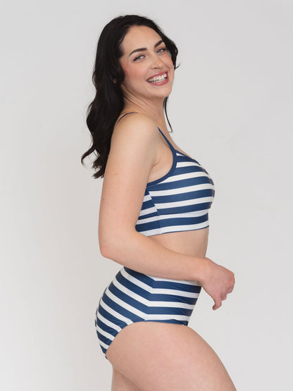 Woman wearing a blue and white striped swimsuit on a plain background