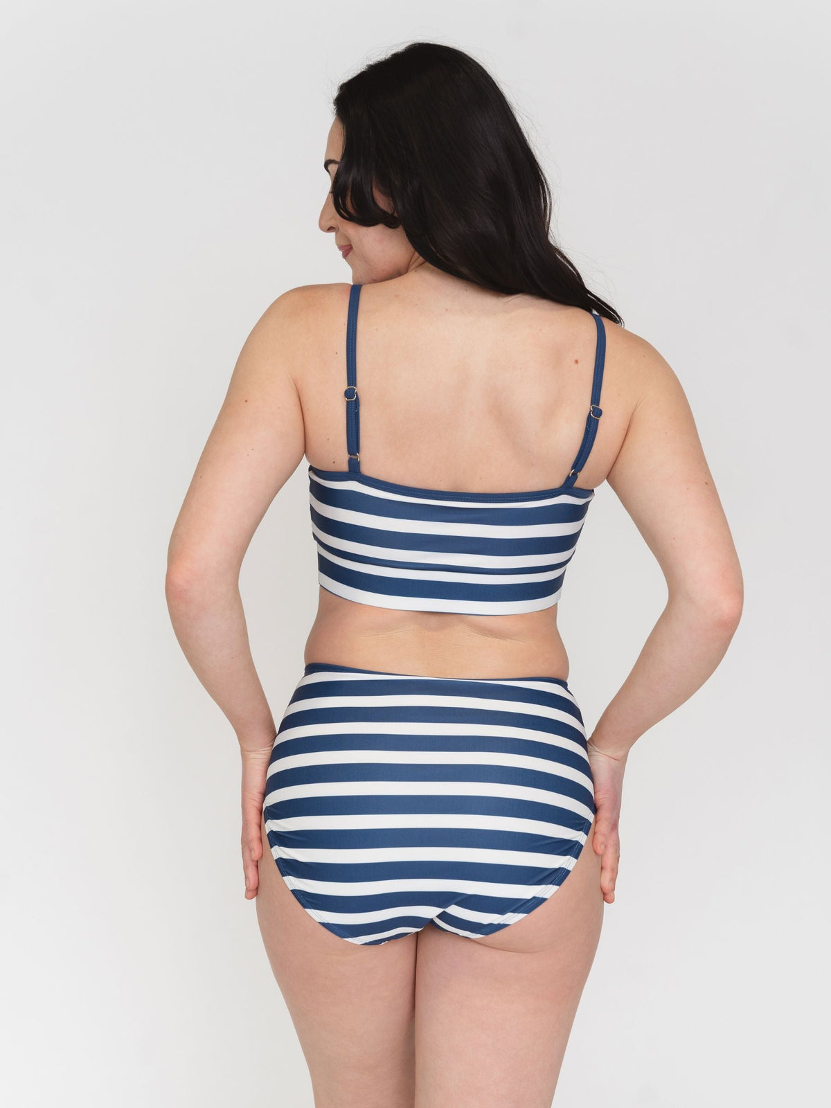 Woman wearing a blue and white striped swimsuit on a plain background