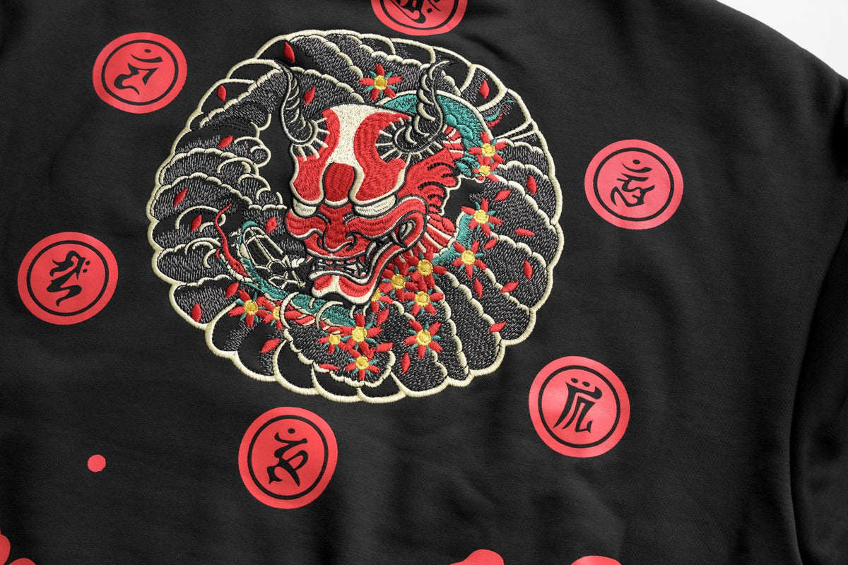 Black garment with red and white design of a stylized animal head surrounded by red circular symbols.