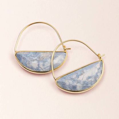Gold hoop earrings with blue stone half-circle pendants on a light pink background