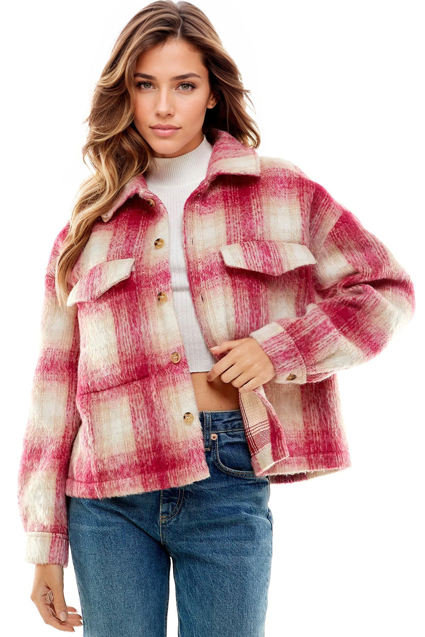 A woman modeling a fuzzy plaid button-front jacket in pink and cream, worn over a white turtleneck and blue jeans against a plain white background.