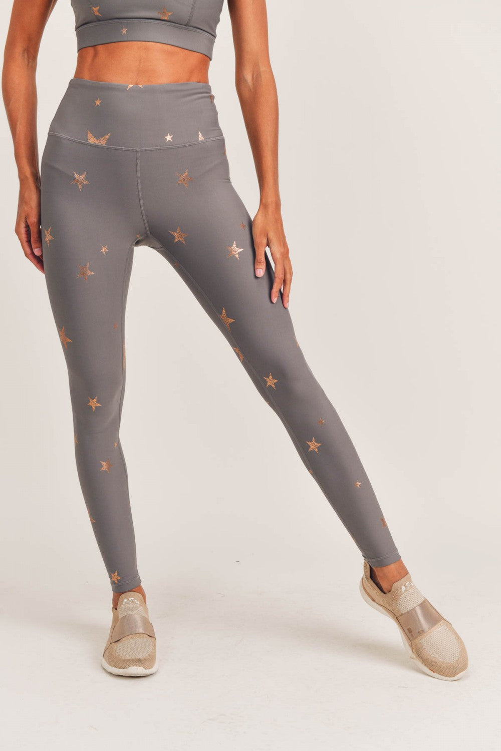 Person wearing gray leggings with star pattern on a white background