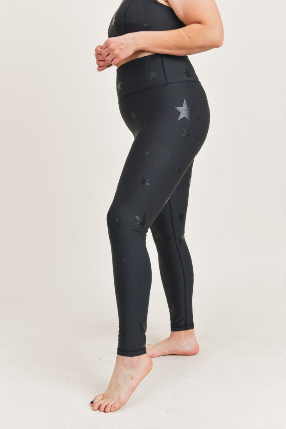 Person wearing black leggings with star patterns on a white background