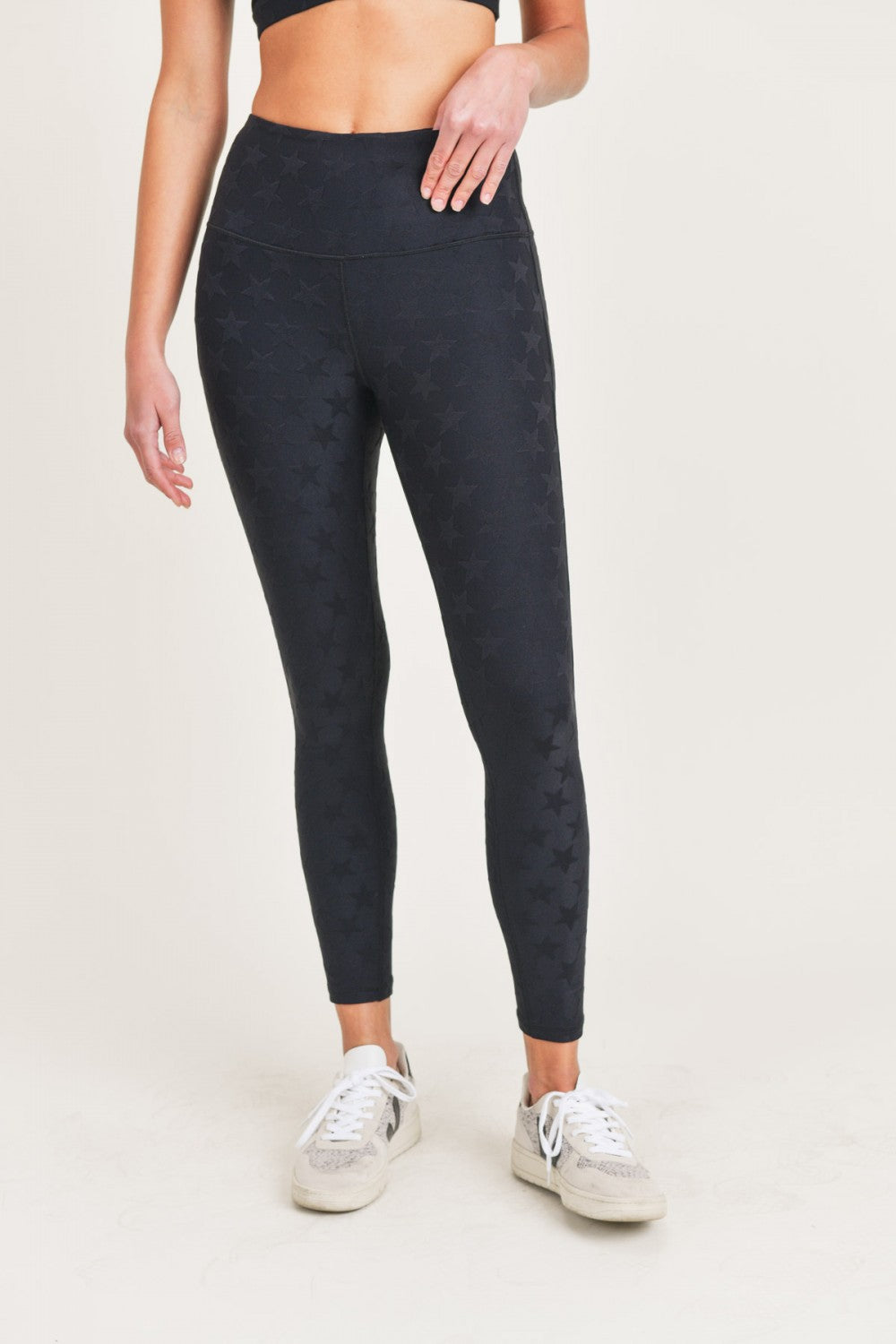 Person wearing black patterned leggings on a light background