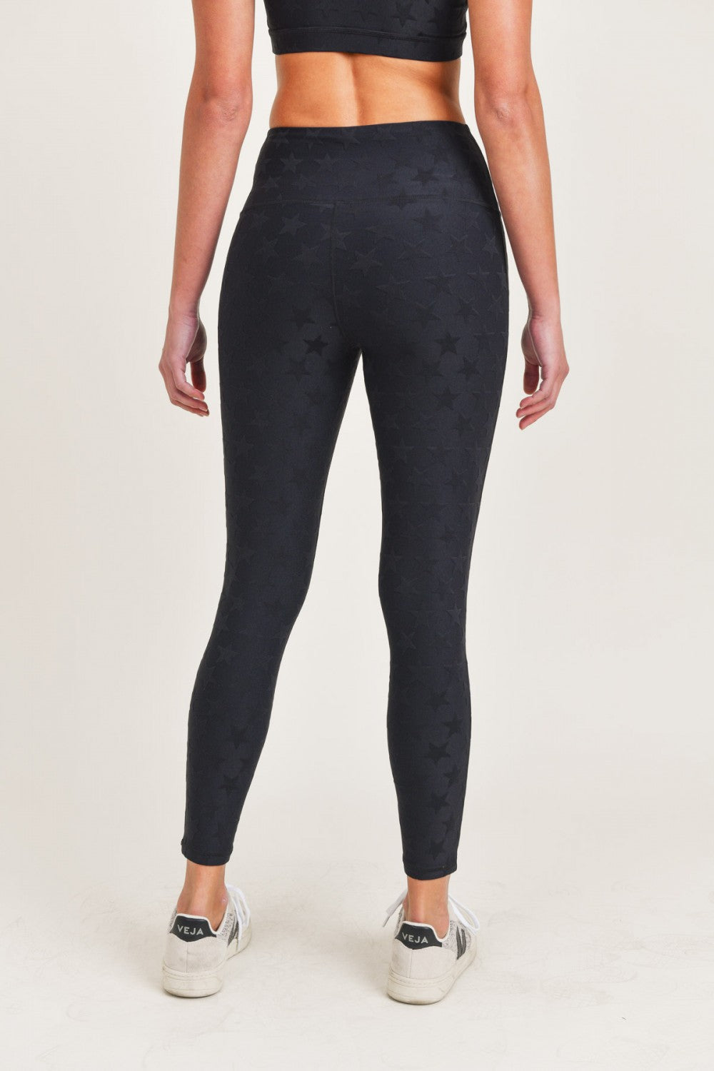 Person wearing black patterned leggings on a white background