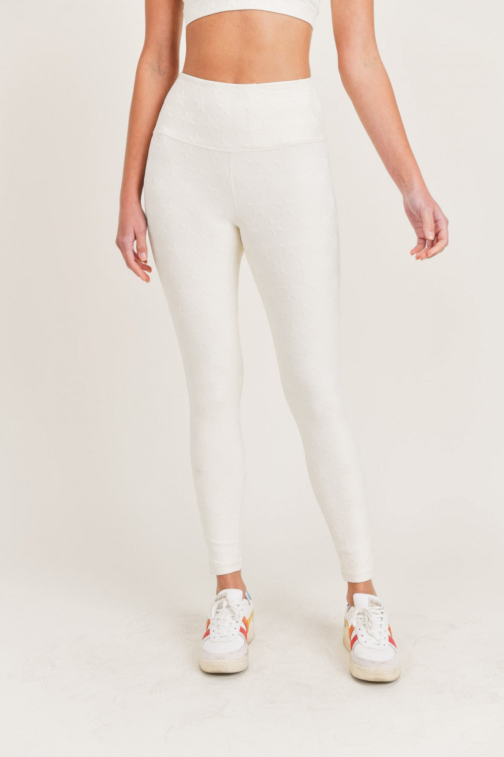 Person wearing white leggings on a plain background