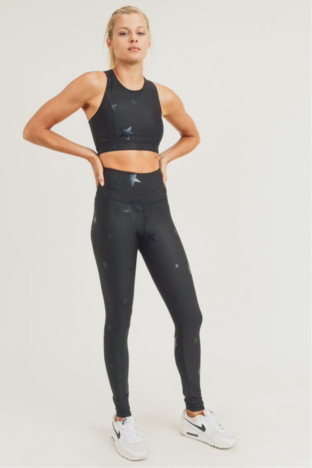 Woman wearing black athletic leggings and sports bra on a white background