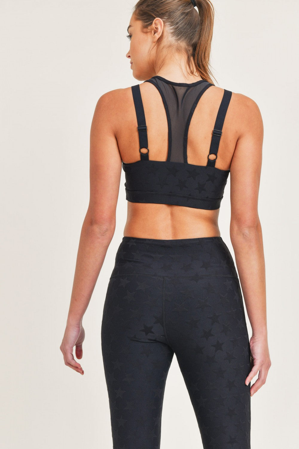 Woman wearing a black sports bra and leggings on a light background