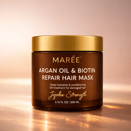 Jar of Maree Argan Oil & Biotin Repair Hair Mask on a reflective surface with a warm background
