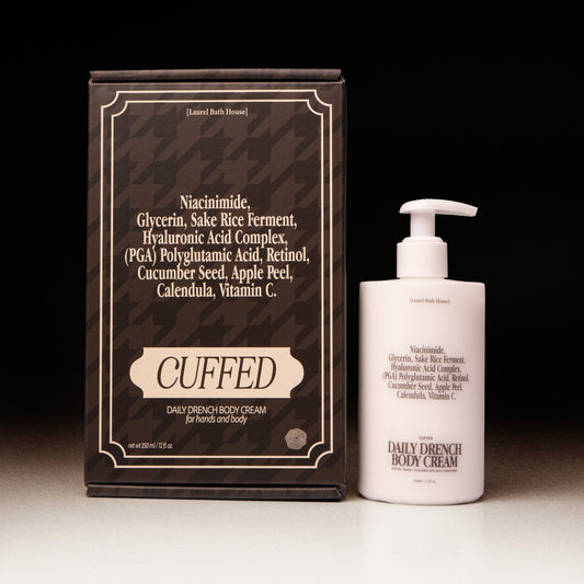 Cuffed Daily Drench Body Cream packaging and bottle on a dark background