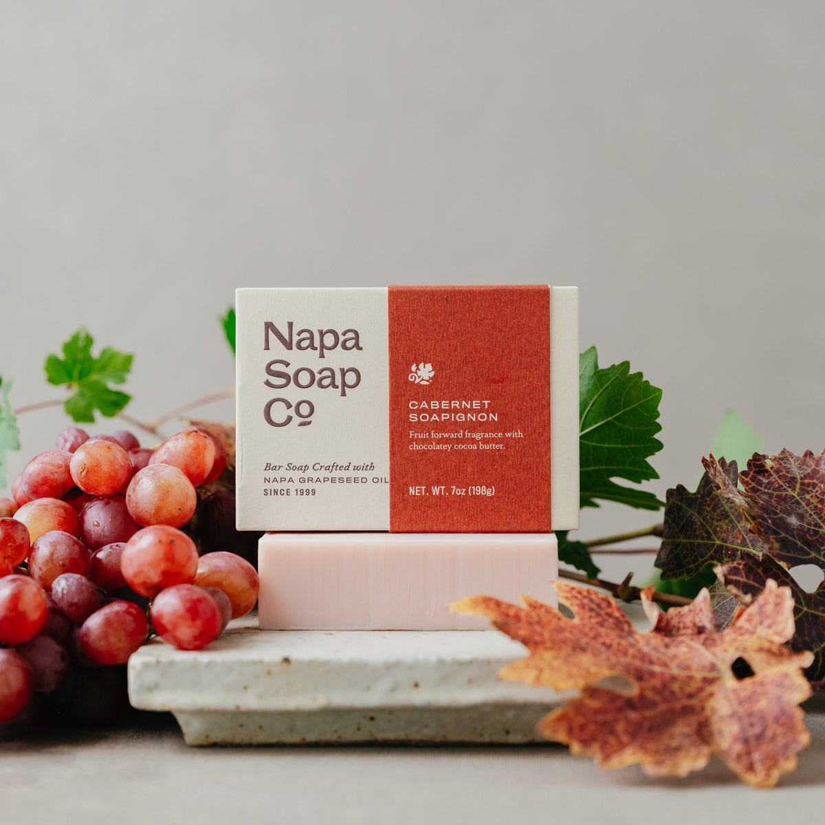 Napa Soap Co. soap bar with packaging on a stone surface with grapes and leaves.