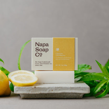 Napa Soap Co. bar soap on a white stand with lemons and greenery on a gray background