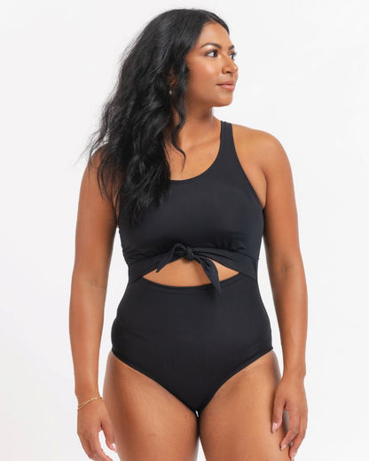 Woman wearing a black swimsuit with cut-out design on a white background