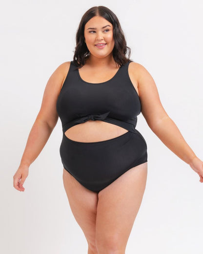 Woman wearing a black swimsuit with cutout design on a white background