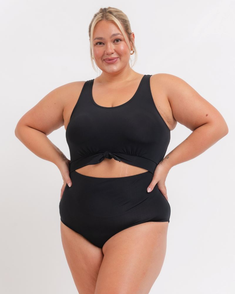 Woman wearing a black swimsuit against a white background