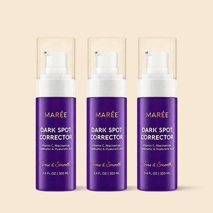 Three MARÉE Dark Spot Corrector pump bottles in a row on a warm beige background. The bottles are deep purple with white pump tops and clear protective caps, featuring gold and white text.