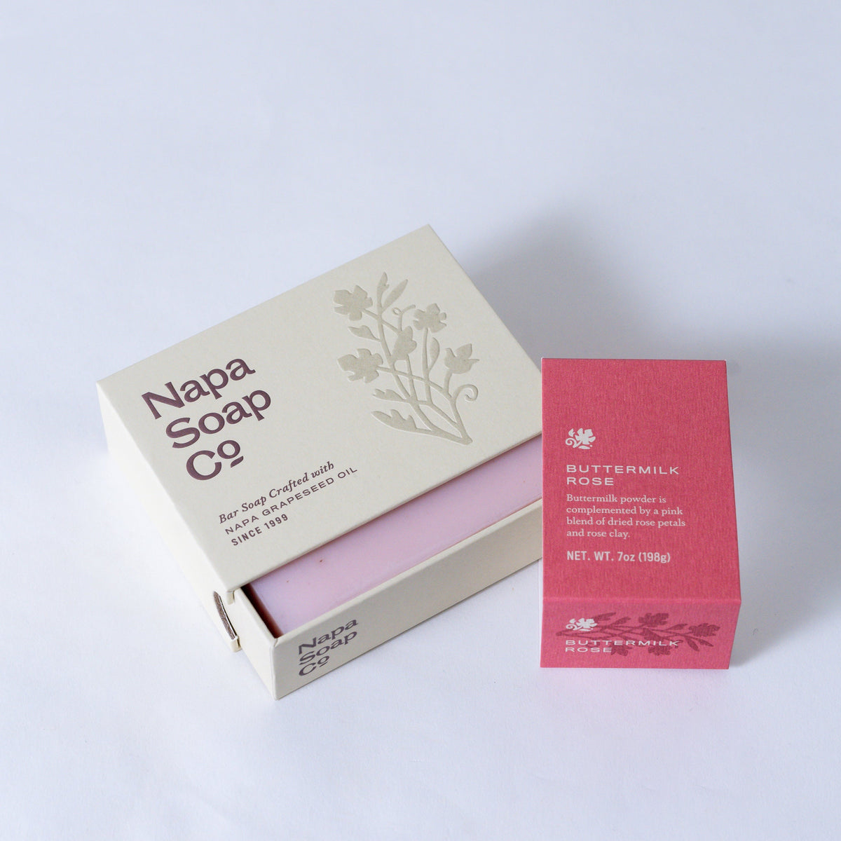 Buttermilk Rose Bar Soap unwrapped beside its carton, on a white background