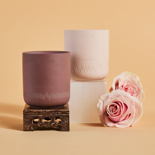 The two Caftari bundle candles styled with pink roses on a beige background