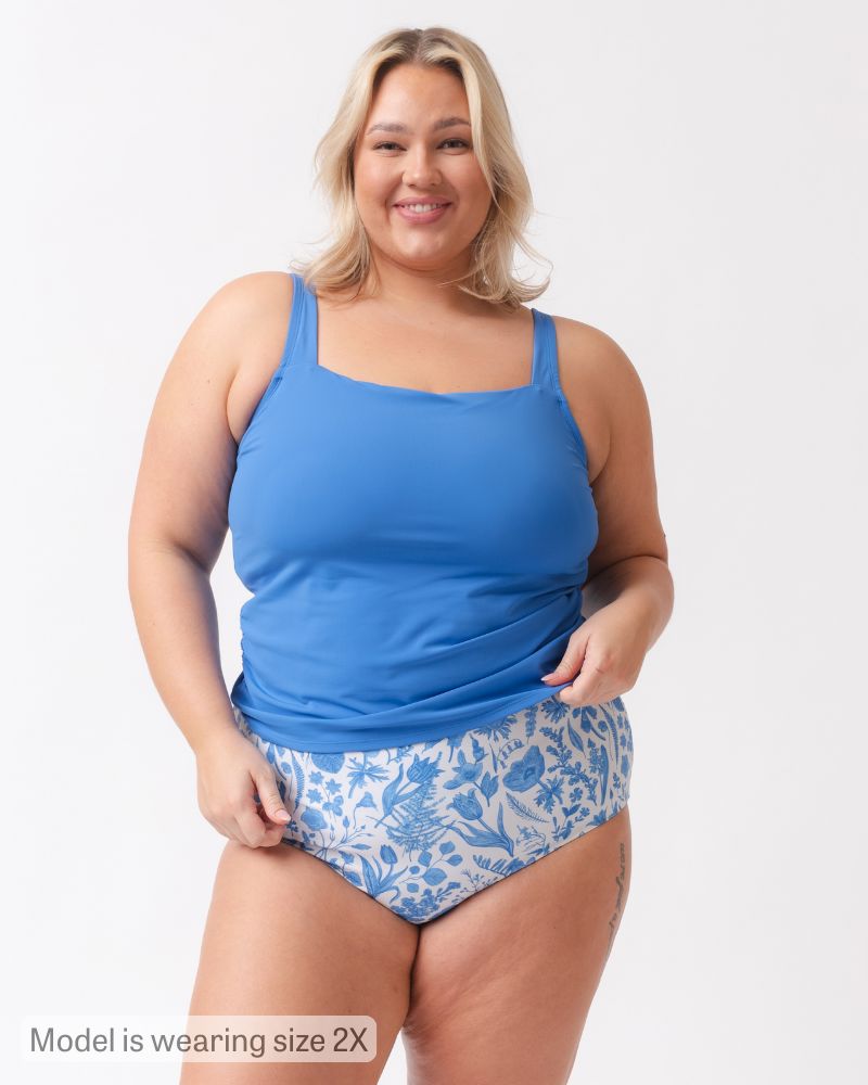 Woman wearing a blue tank top and floral high-waisted shorts on a white background