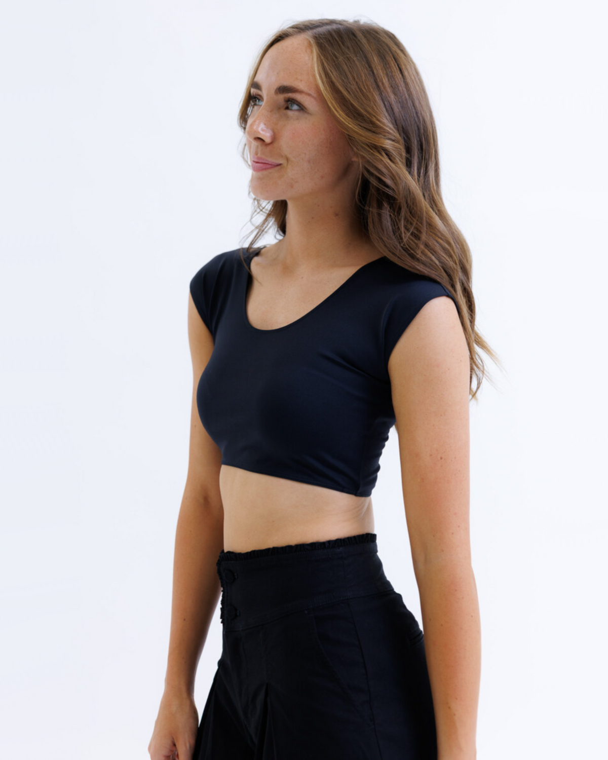 Woman wearing a black crop top and skirt on a white background