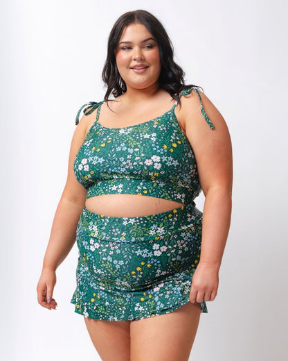 Woman wearing a green floral two-piece swimsuit on a white background