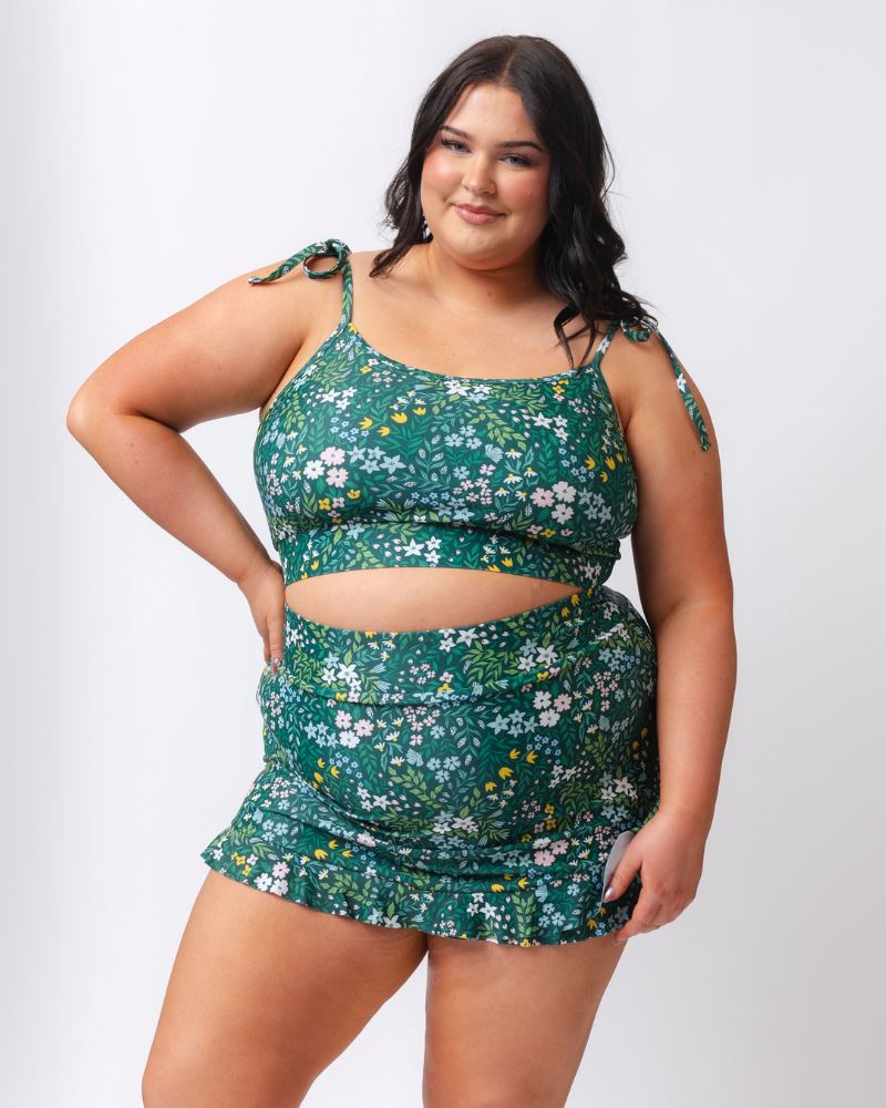 Woman wearing a green floral two-piece outfit on a white background