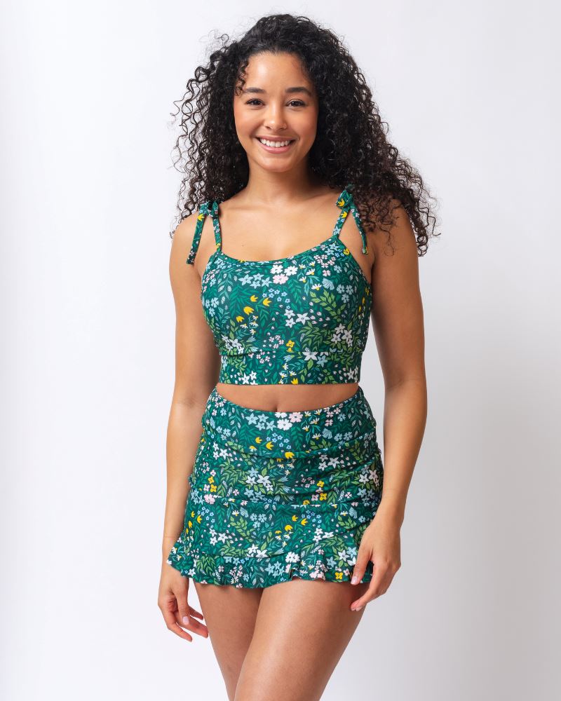 Woman wearing a green floral two-piece swimsuit on a white background