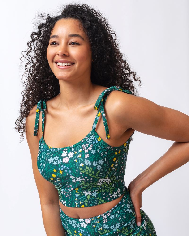 Woman wearing a green floral top and pants on a white background