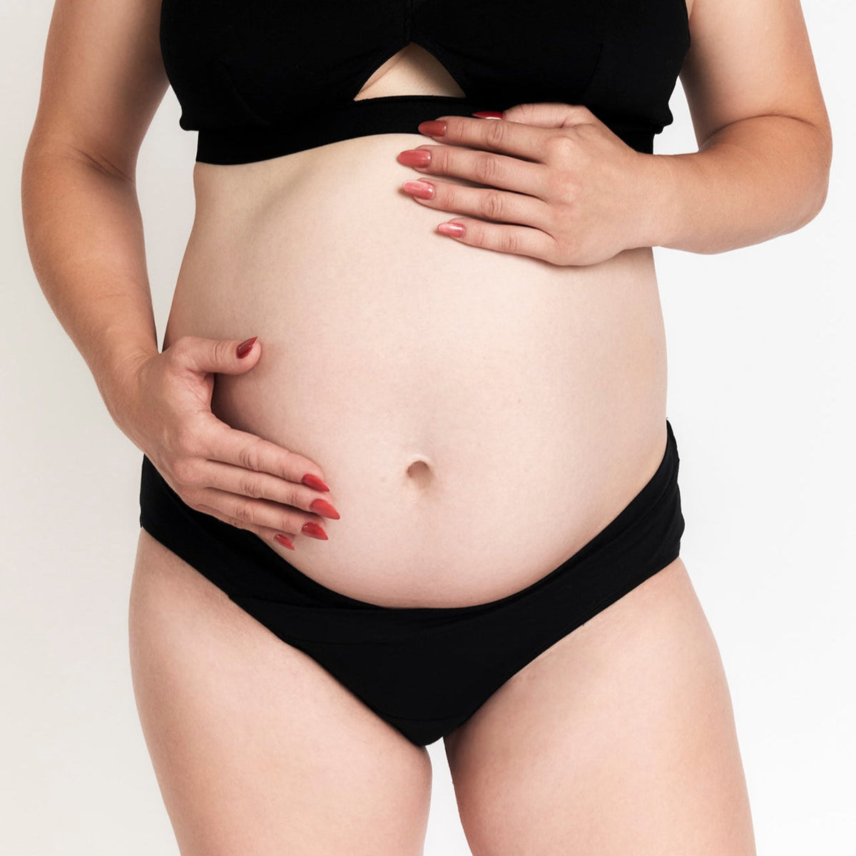 Organic Cotton Maternity Brief in Black, on a pregnant model holding her belly, light background