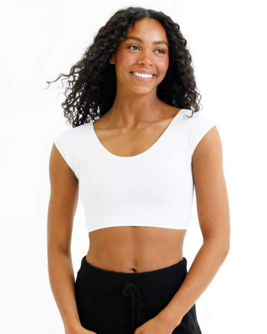 Woman wearing a white crop top and black pants on a white background