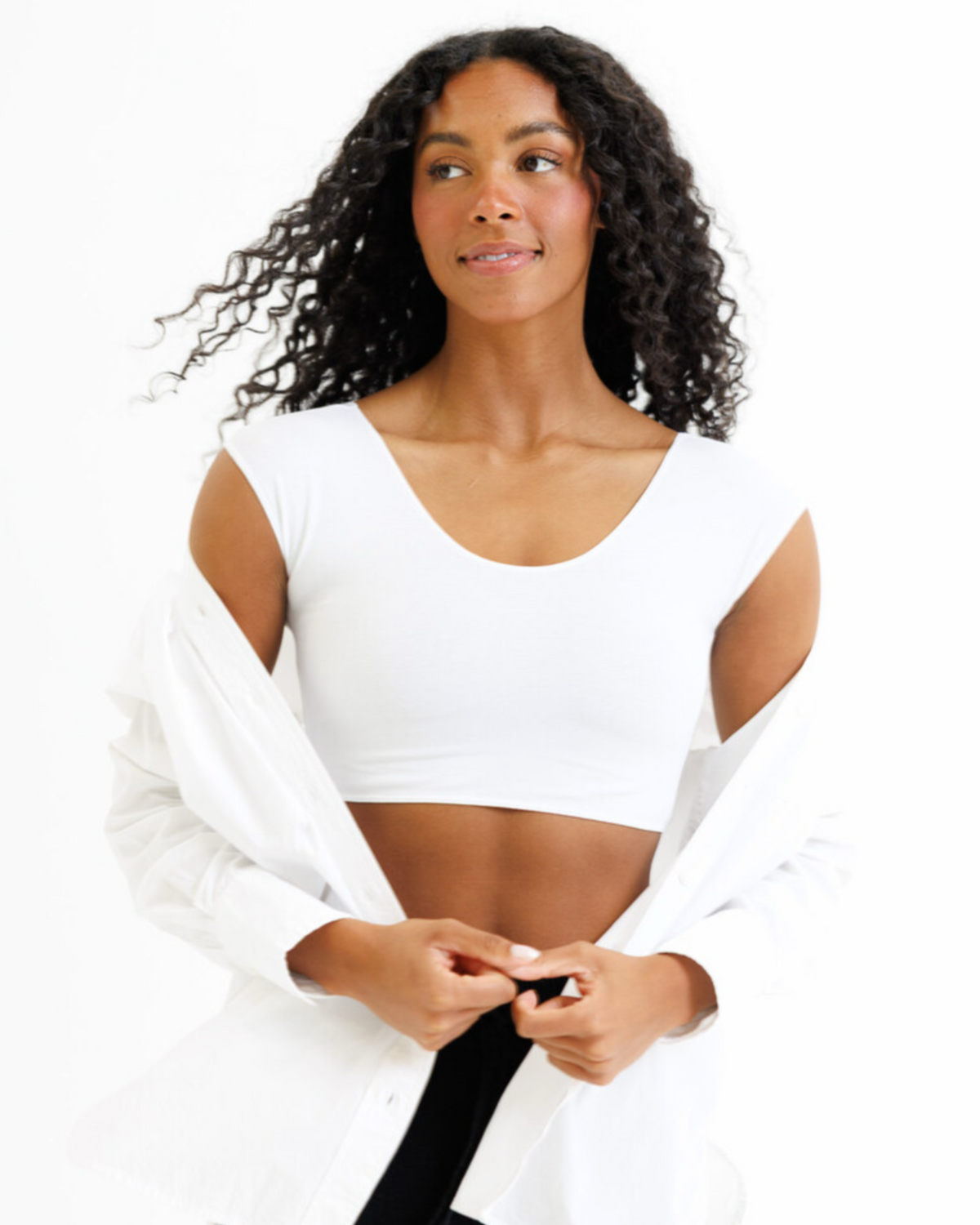 Woman wearing a white sports bra and long-sleeve cover-up on a white background
