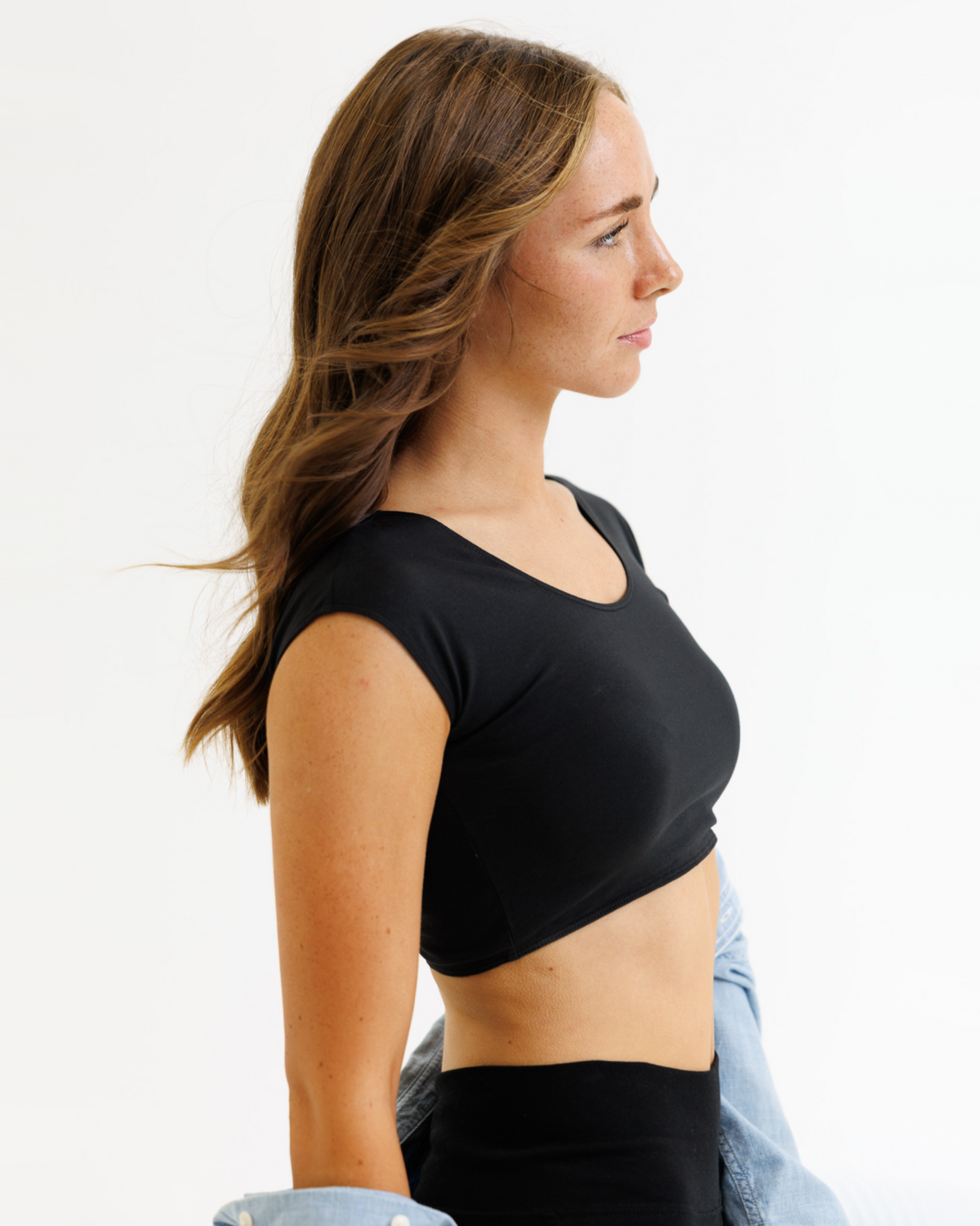 Woman wearing a black crop top with a plain background