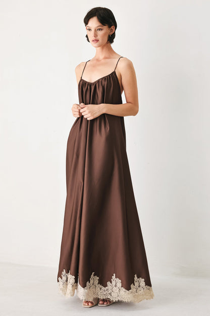 Woman wearing a brown slip dress with lace trim on a white background