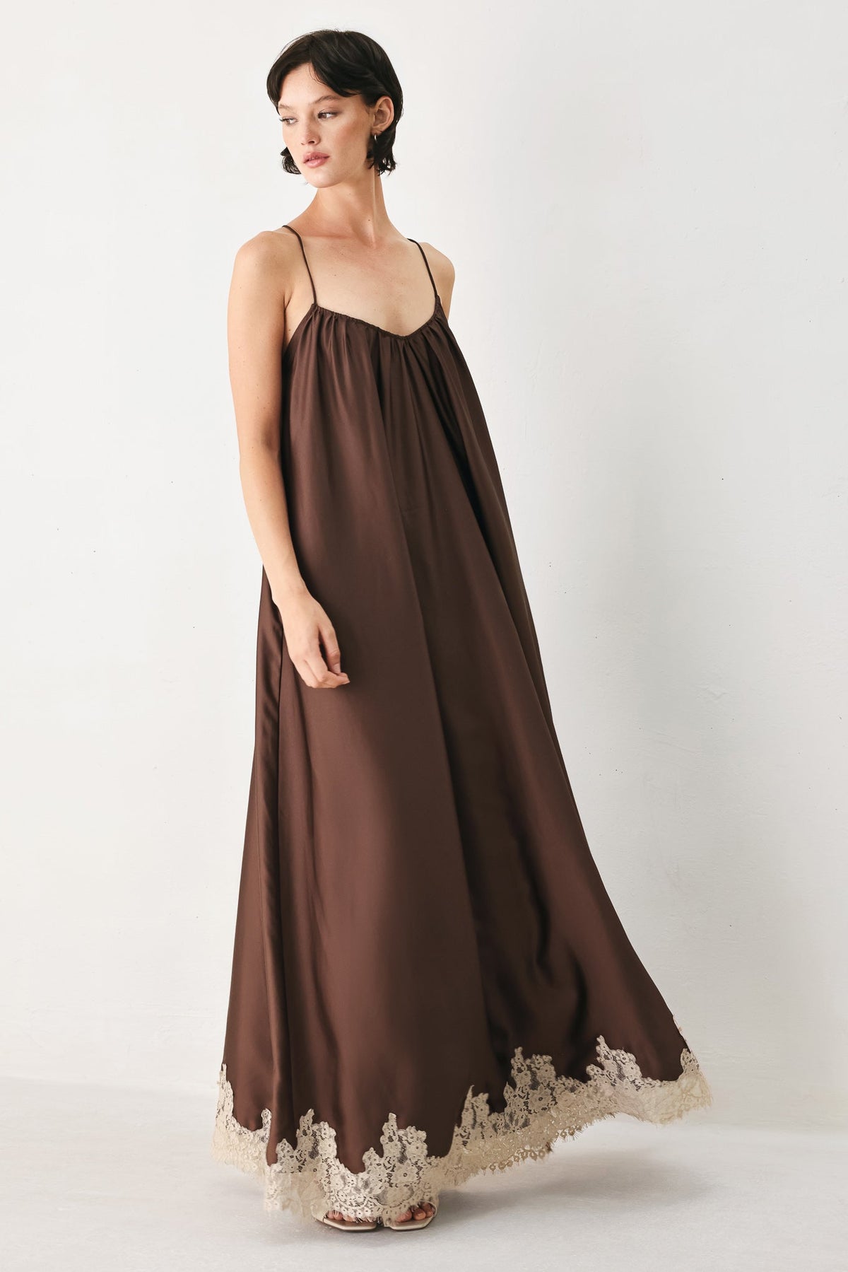 Woman wearing a brown dress with lace details on a white background