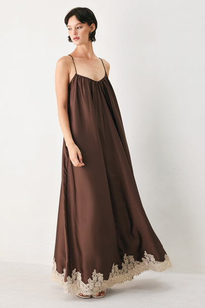 Woman wearing a brown dress with lace details on a white background