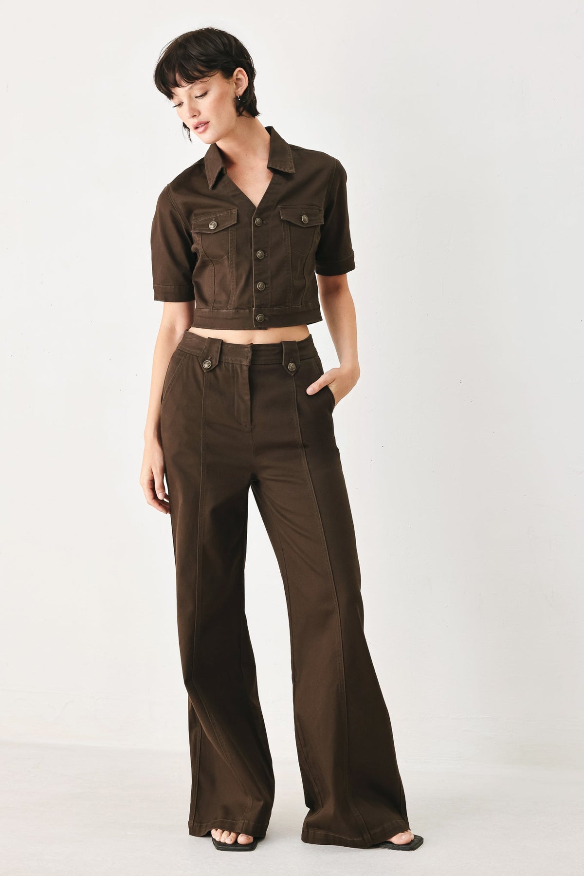 Back view of the cropped brown denim jacket on a model against a plain background.