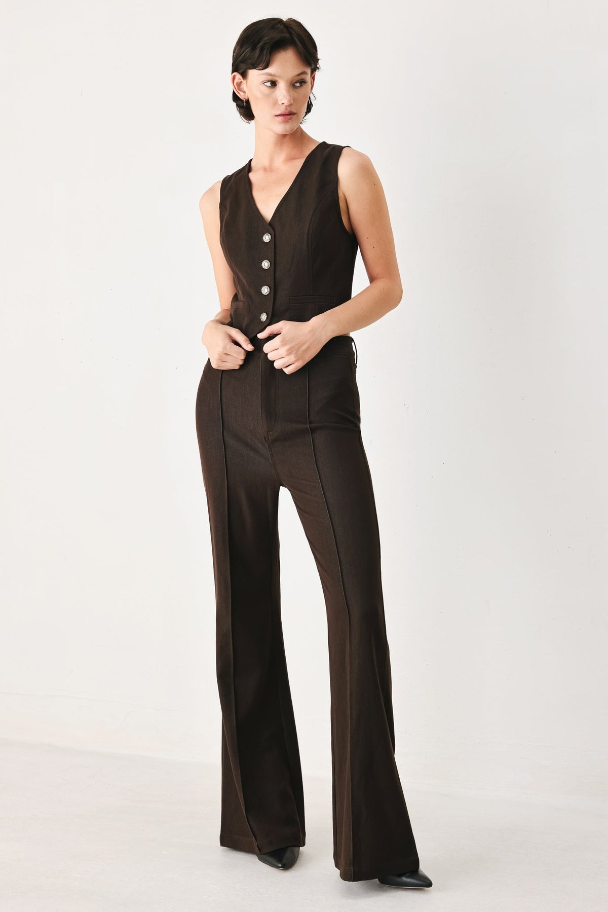 Brown sleeveless woven vest worn on its own over bare arms.