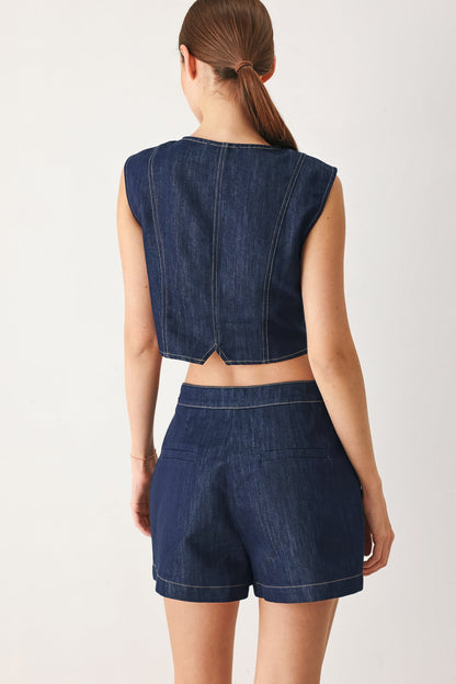 Back view of the cropped indigo denim vest on a model against a plain background.