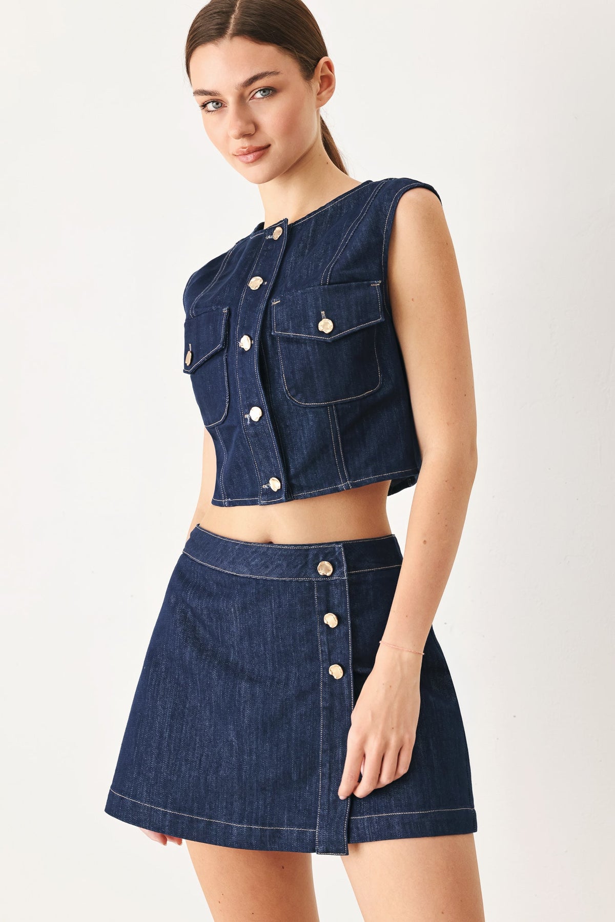 Close-up of the button closure on the Iconic Indigo denim crop vest.