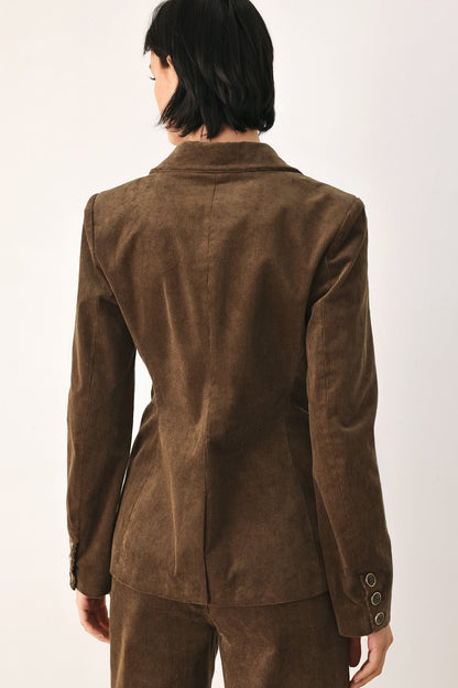 A person shown from the back wearing a brown suede or nubuck blazer with matching trousers against a plain light background.