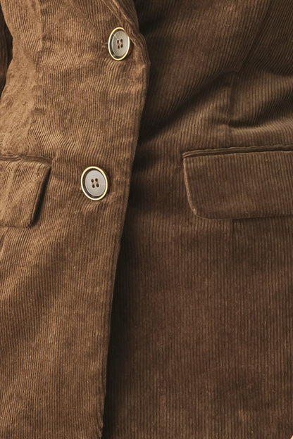 Close-up of a brown corduroy jacket or coat showing the buttoned front, a chest pocket, and the ribbed fabric texture.