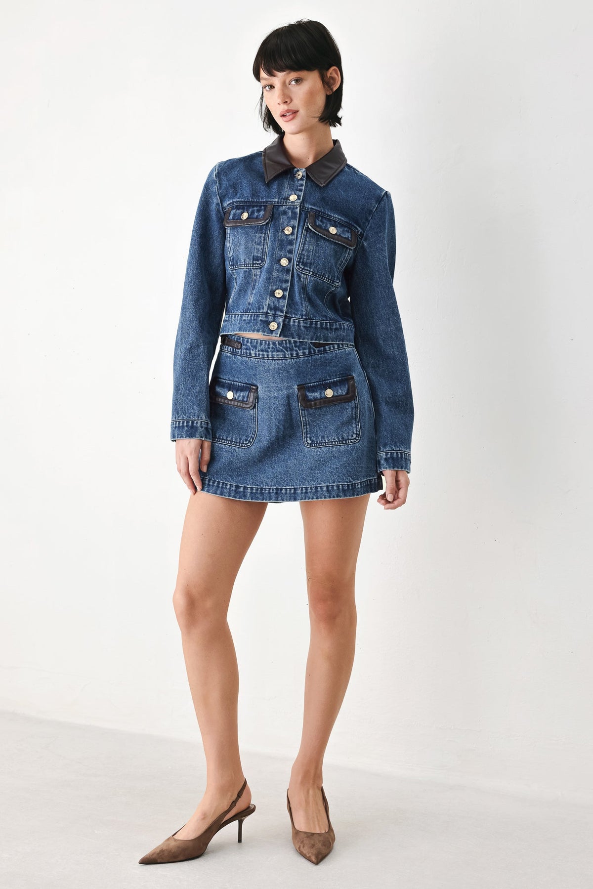 Washed denim crop jacket with a front closure and contrast faux leather collar.