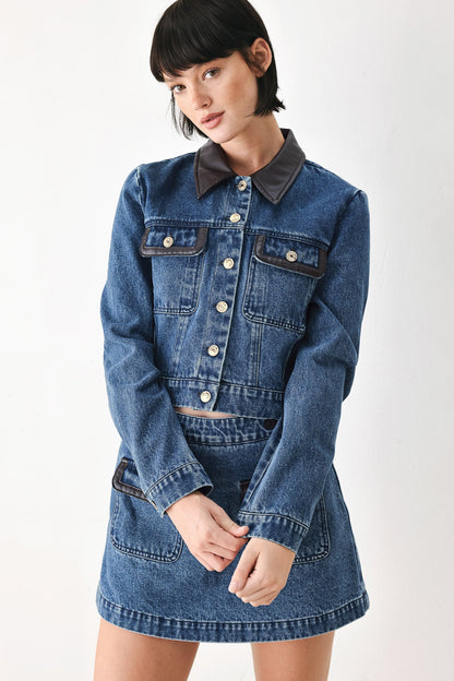 Long-sleeve cropped denim jacket with faux leather collar and pocket detailing.