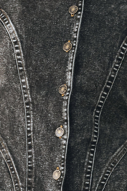 Close-up of a dark gray denim jacket showing the buttoned front closure with decorative round metal buttons and contrast stitching.