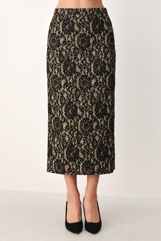 A black and beige floral lace midi skirt shown on a model from the waist down, paired with black pointed-toe heels against a plain off-white studio background.