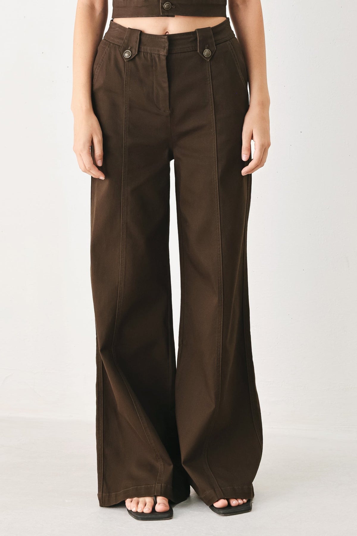 Brown wide-leg pants shown on a model against a plain studio background.