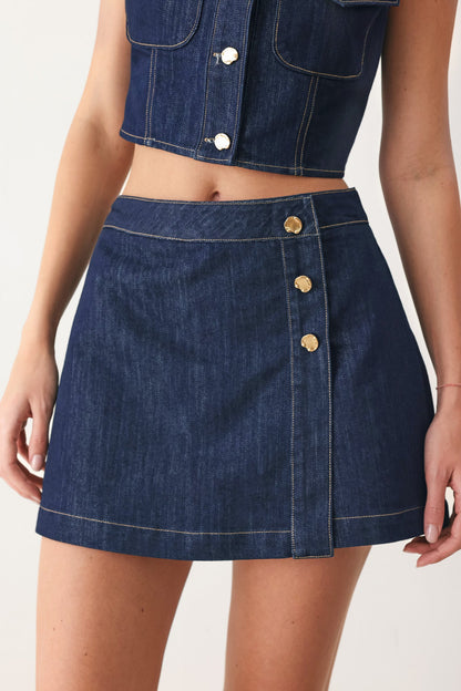 Indigo denim skort with a button front, shown on a model against a plain studio background.