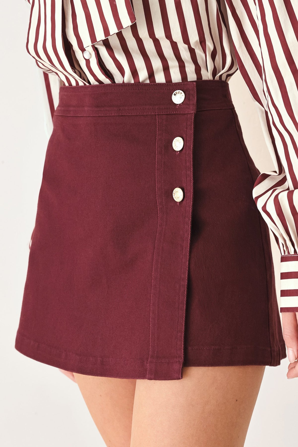 Close-up of the button details and clean front closure on the burgundy skort.