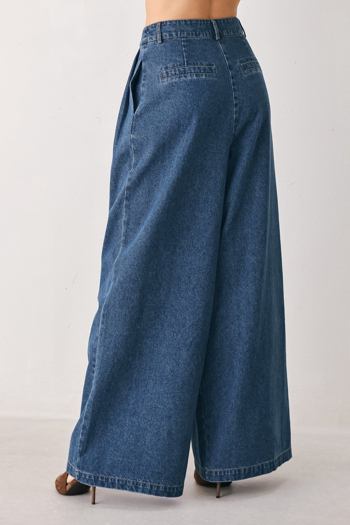 Wide-leg medium indigo denim pants showing the pleated front and long 44-inch leg.